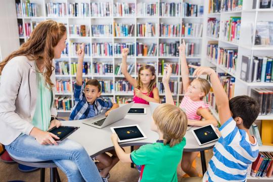 Lehrerin mit Klasse arbeitet auf Tablets.